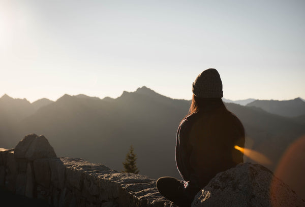 Person sitting on a mountain watching the sunset