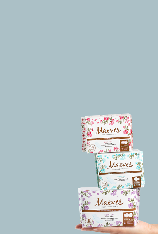 Woman holding all three boxes of Maeves pads with a light blue background